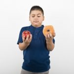 kid comparing apple and donut