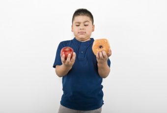 kid comparing apple and donut
